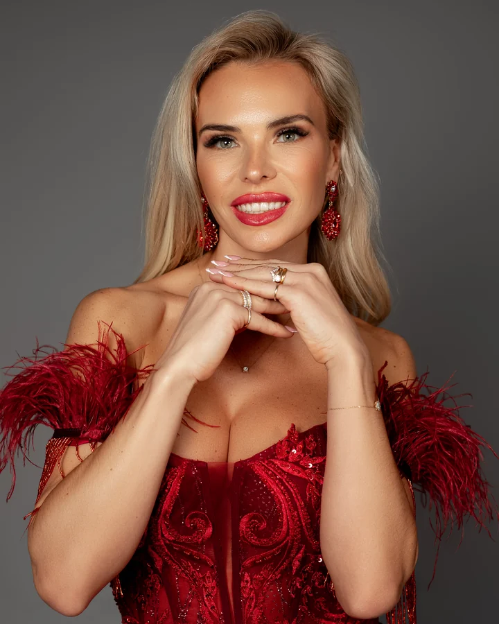 Beauty portrait of a smiling blonde woman in a red feathered corset