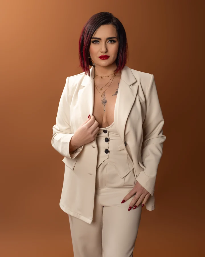 Personal branding portrait of a woman in a cream suit against a bronze backdrop