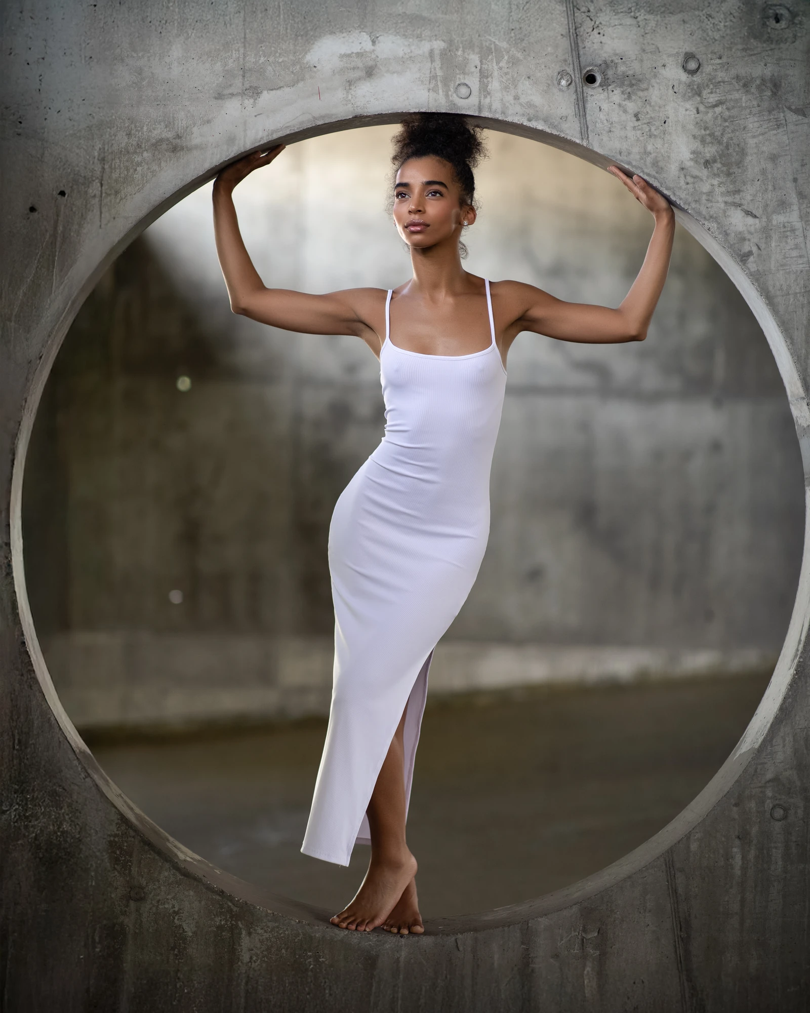 Editorial portrait of a woman in a white dress framed by a concrete circle